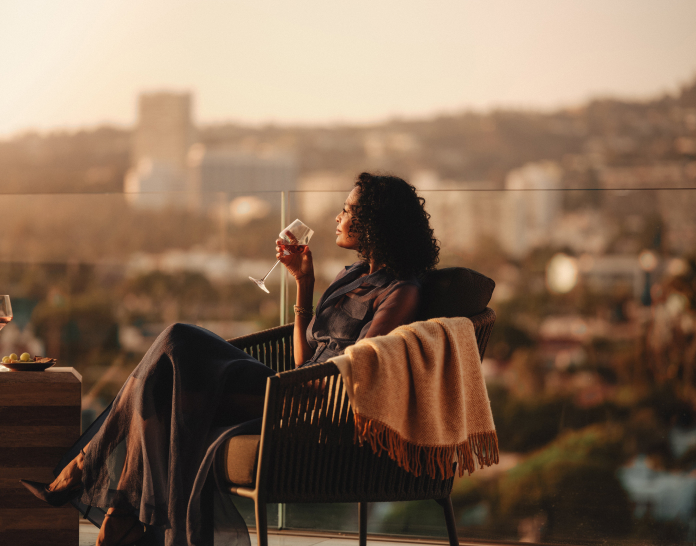 A couple sits outside drinking wine on their large terrace that overlooks West Hollywood.