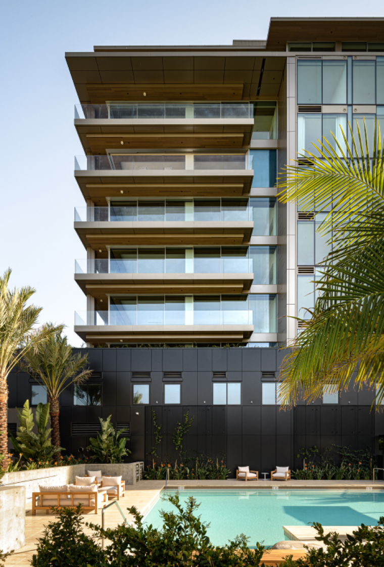 Six balconies in a luxury condo building rise above a sunny resort-style pool area.